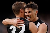 Two Collingwood AFL players embrace as they celebrate a goal against Carlton.