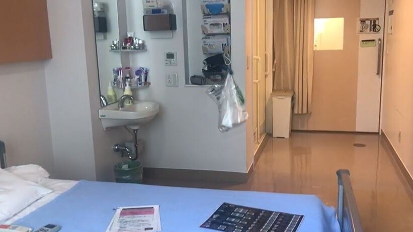 A shot of a hospital room including a sink and bed