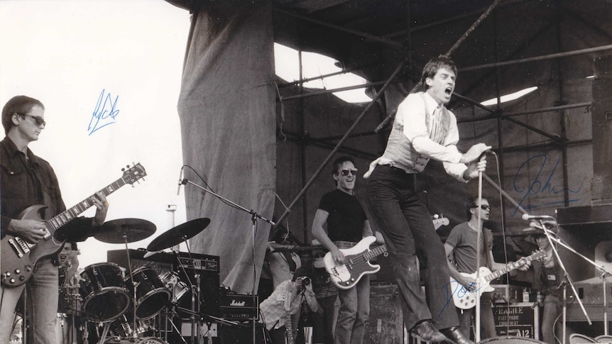 Autographed photo of Doc Neeson and The Angels in full flight.