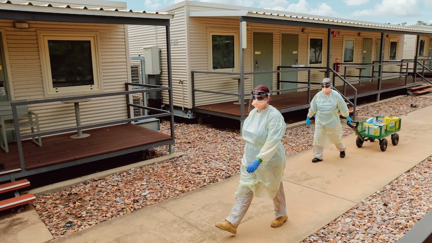Specialist health teams in protective gear walk through the Howard Springs quarantine facility.
