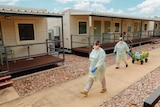 Specialist health teams in protective gear walk through the Howard Springs quarantine facility.