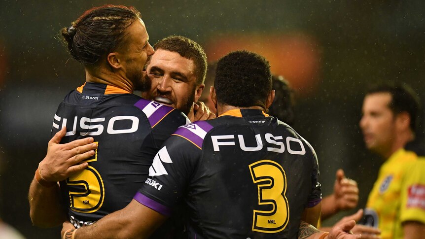 Rugby league players hug and smile as they celebrate a win over their opposition.