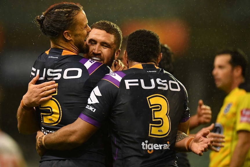 Rugby league players hug and smile as they celebrate a win over their opposition.