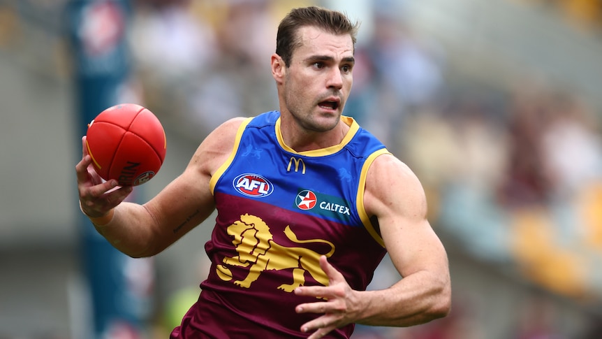 A footballer takes a Sherrin in hand and looks to pass it.