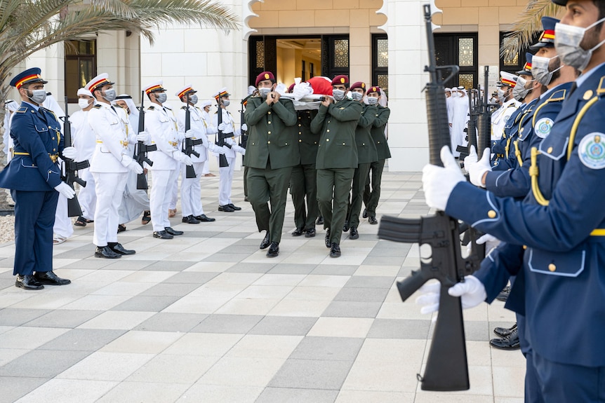 Soldiers carry body of late president through honour guard.