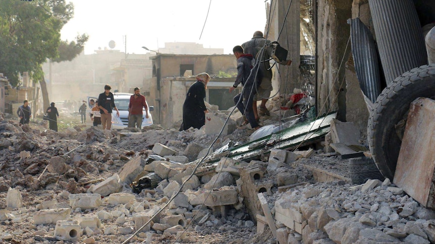 People inspecting damage from airstrikes on a market in Atareb.