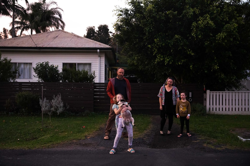 Sunny, her partner Ramesh, and kids Israel and Miette stand by the road in front of their home.