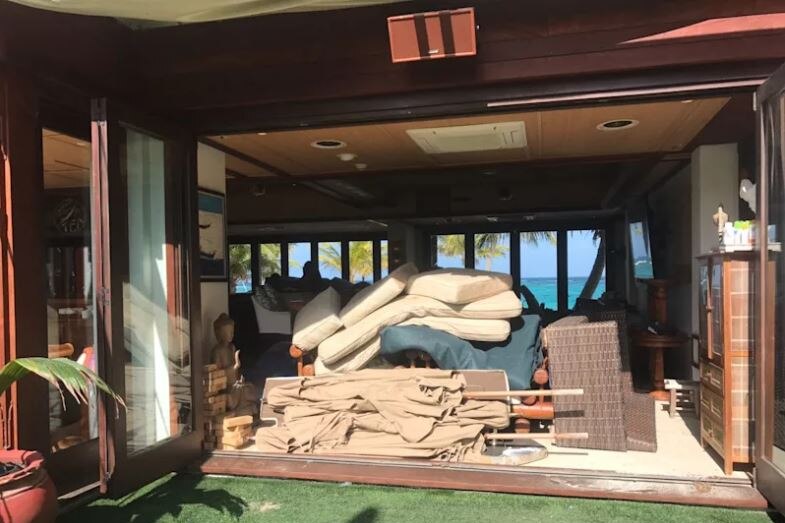 Outdoor furniture is seen stacked inside a building.