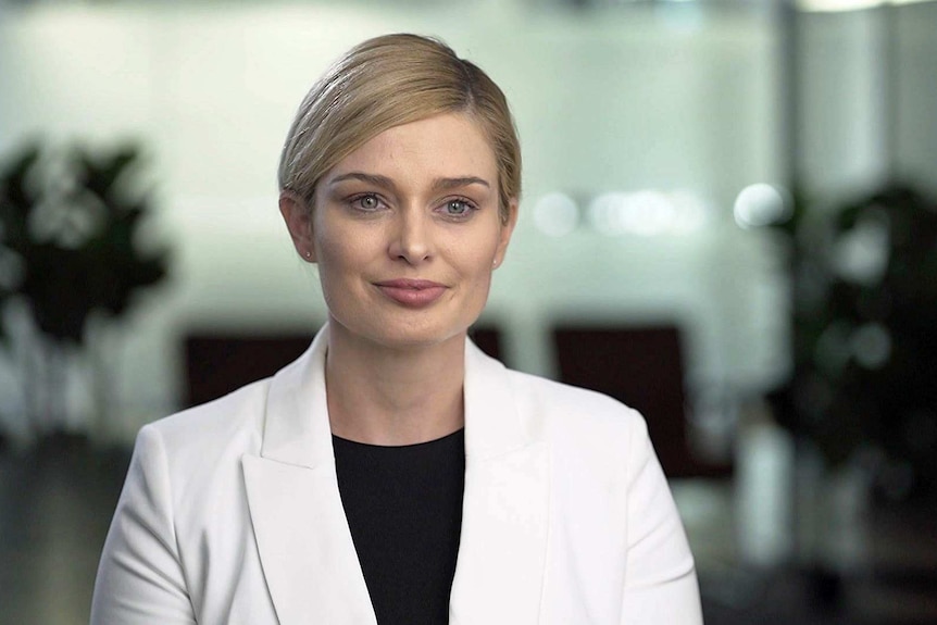 A blonde woman wearing a white jacket over a black round-neck shirt