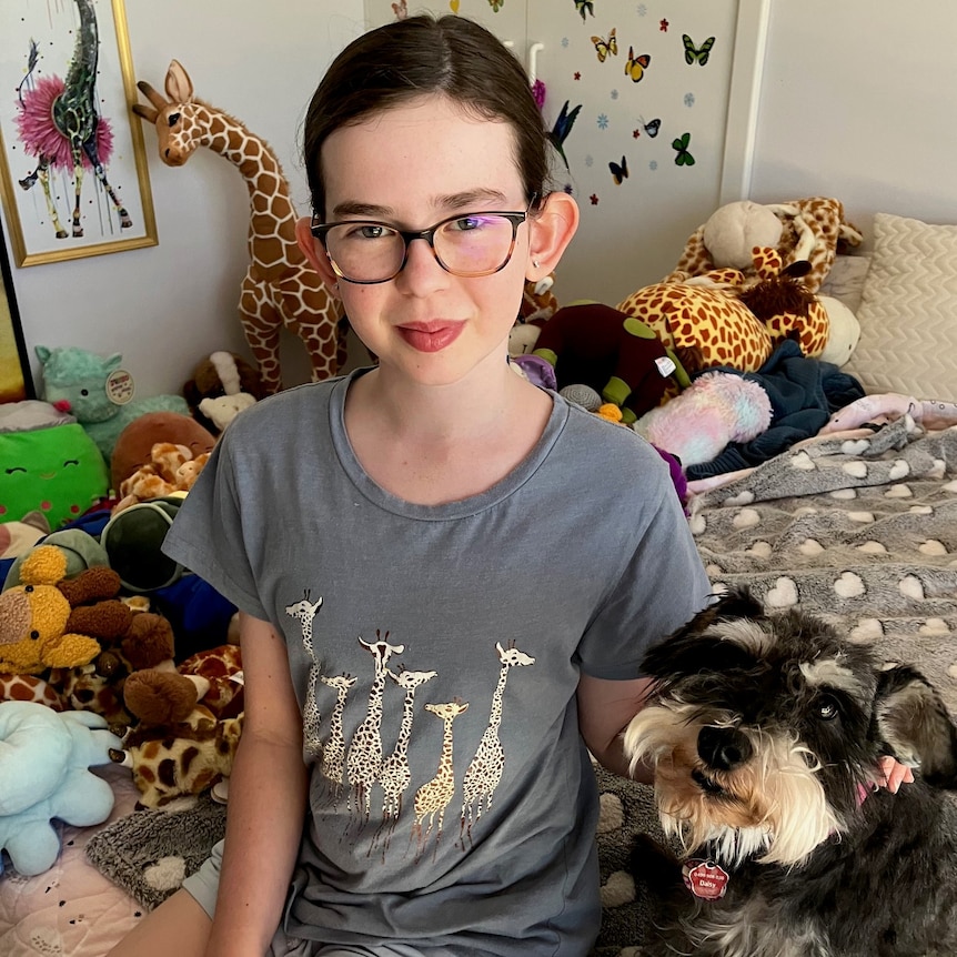 Thalia Keenan cuddles her dog while sitting in her bedroom.