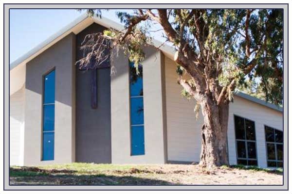 a beige building featuring a cross and tall, narrow windows 