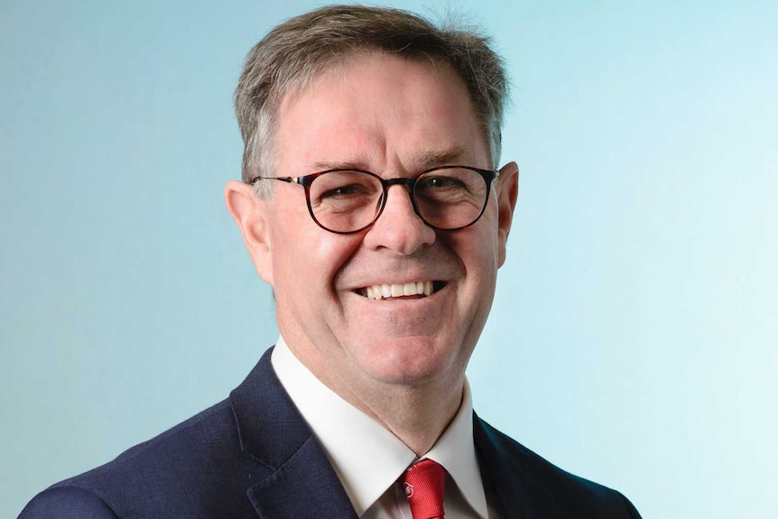 Professional photo of the chief executive of SA Health, wearing a suit with a blue background