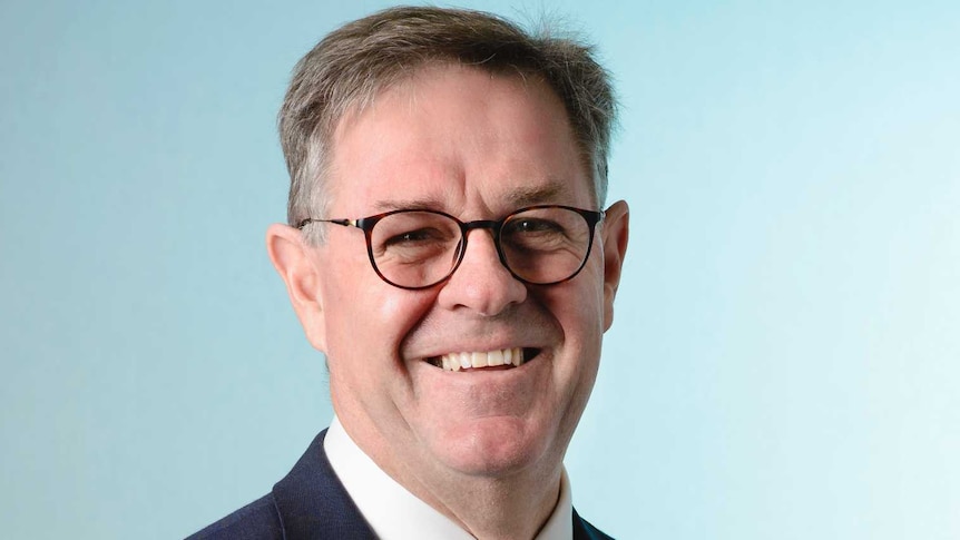 Professional photo of the chief executive of SA Health, wearing a suit with a blue background