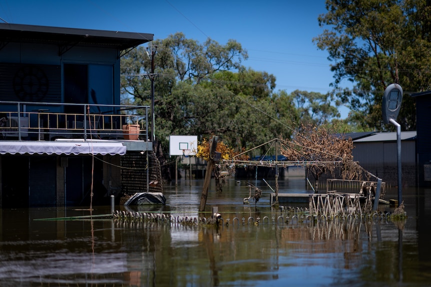 A badly flooded residential property beneath a clear sky.