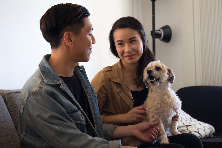 Mikey and Heidi Tai play with their dog Simba in lounge room.