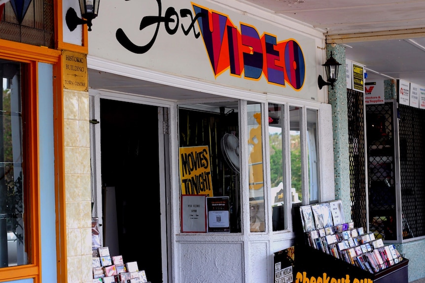 A store with a colour logo and shelves of DVD's out the front.