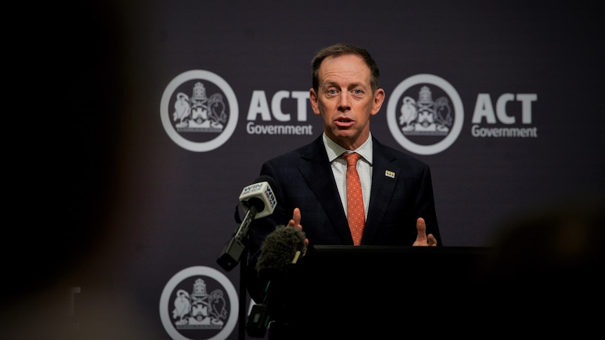 Attorney-General Shane Rattenbury at a podium in a suit. 