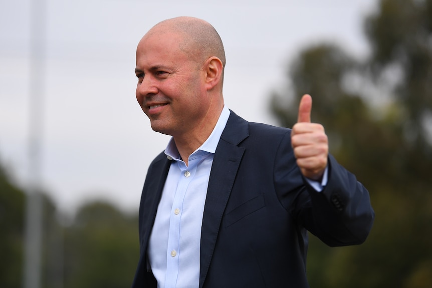 Josh Frydenberg gives a thumbs up while walking outside.