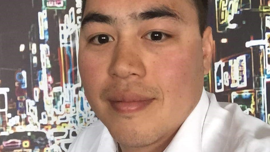 A headshot of Andrew Doan in a white shirt with a city skyline neon lights in the background