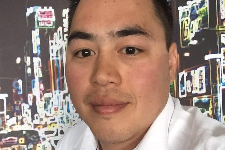 A headshot of Andrew Doan in a white shirt with a city skyline neon lights in the background