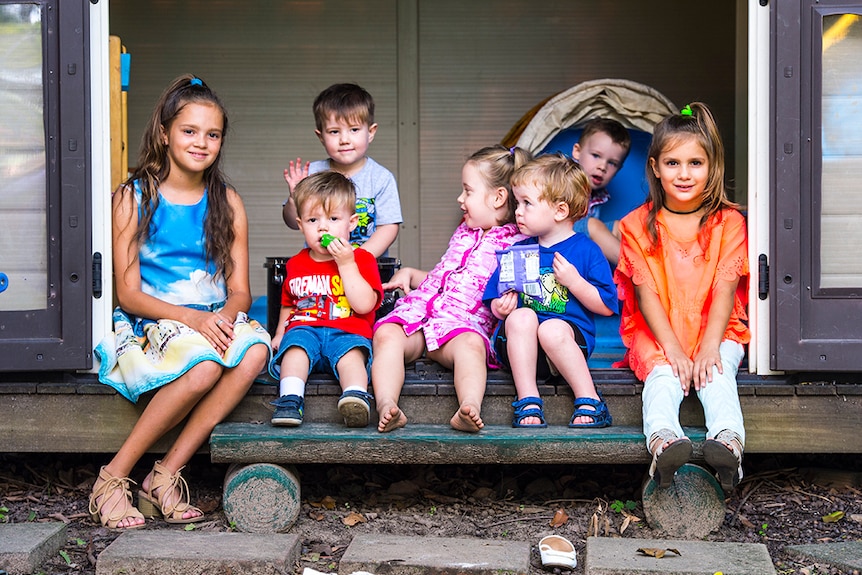 Children of different ages sitting together on a porch in the City of Logan, south of Brisbane.