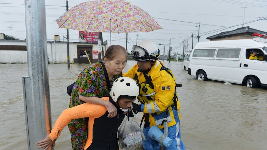 A woman is rescued by police officers at a flooded residential area in Japan