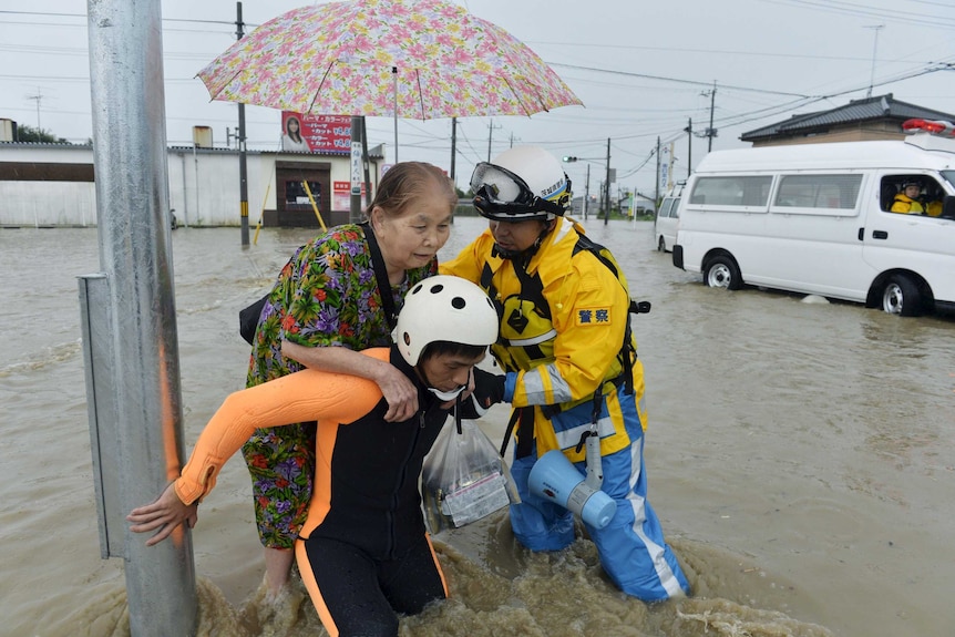 A woman is rescued by police officers at a flooded residential area in Japan