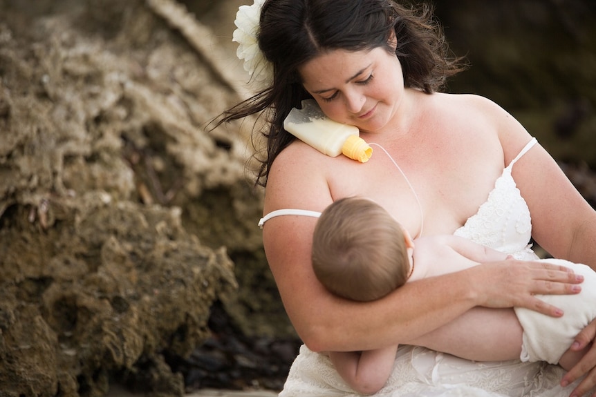 A woman feeds her baby using a supply line.