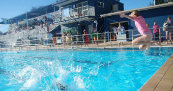 Kids jump into the local public pool in Orange.