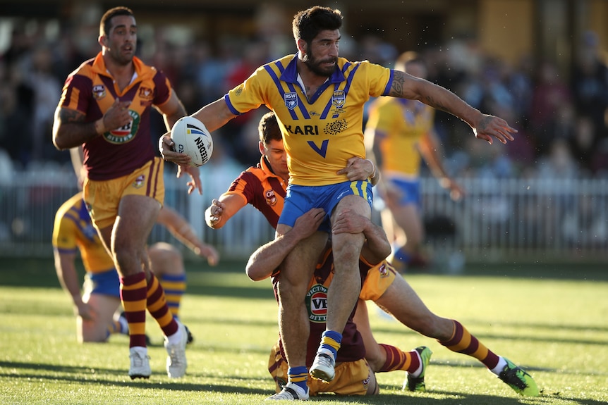 A rugby league player looks to offload during a match 