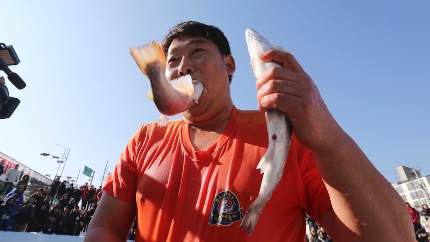 Man puts trout in his mouth