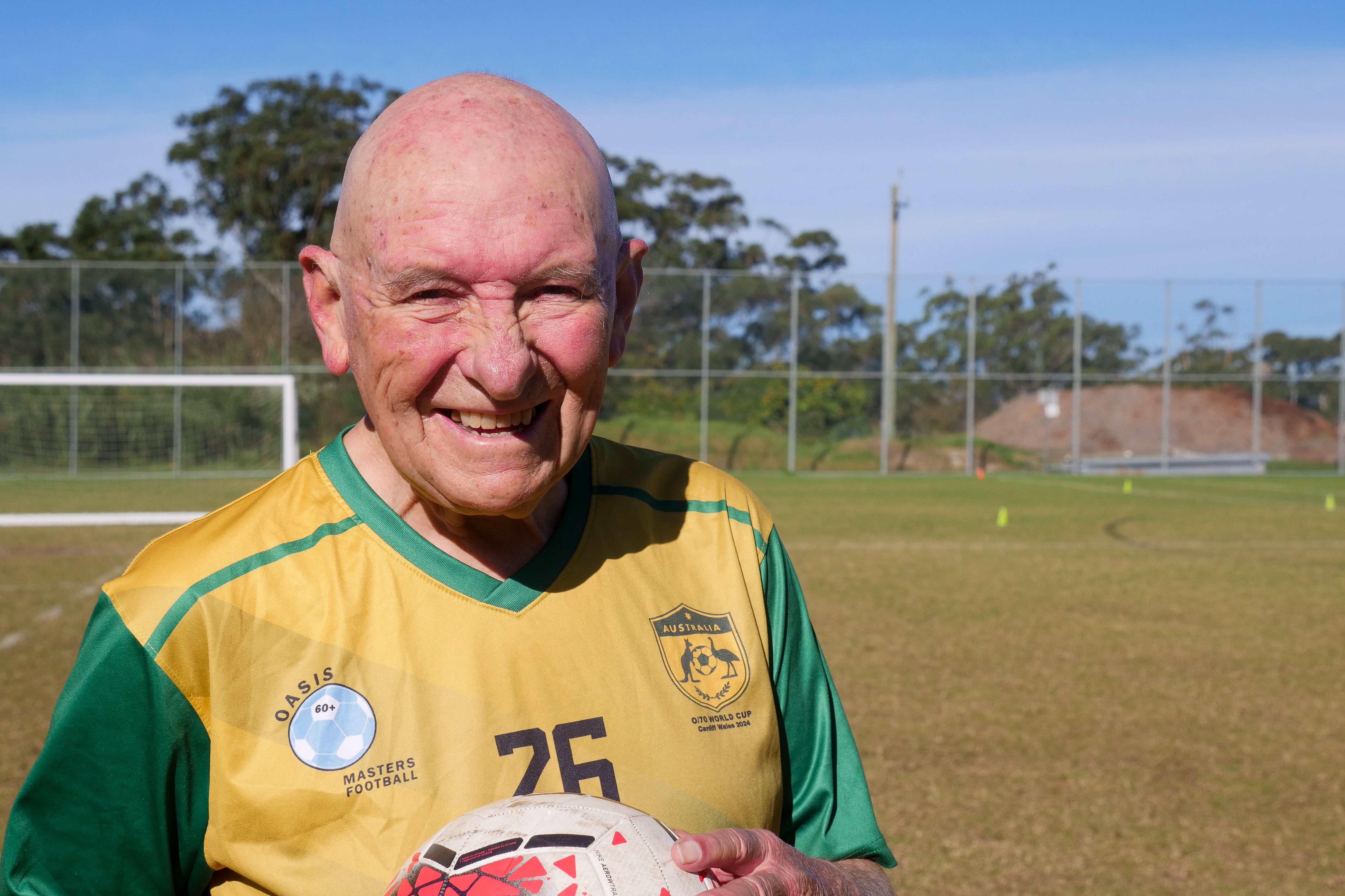 a bald older man smiles wearing a football jersey