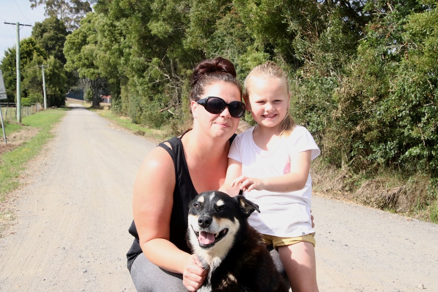 Dark haired woman in sun glasses with fiveyear old daughter and happy dog 