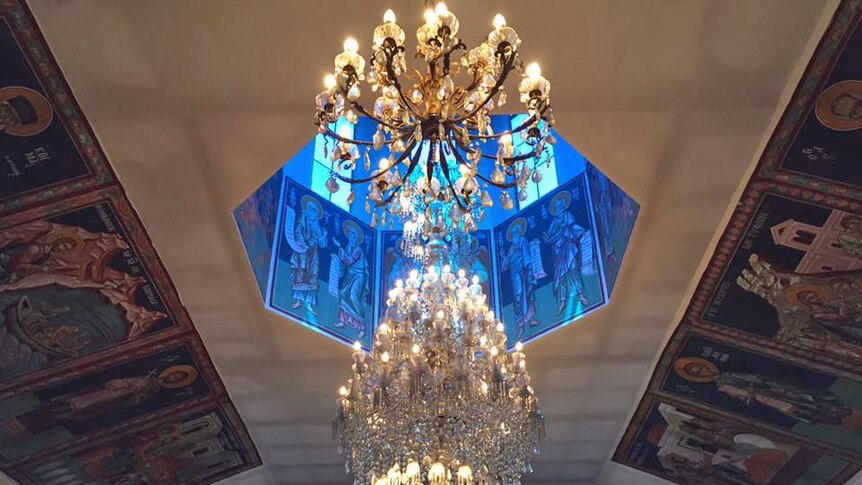 A large, glass chandelier hanging under a blue dome