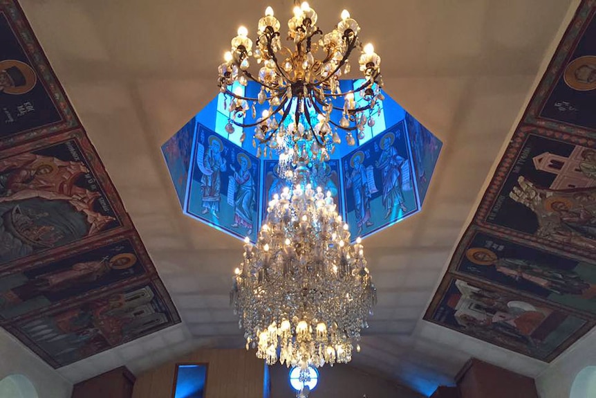 A large, glass chandelier hanging under a blue dome