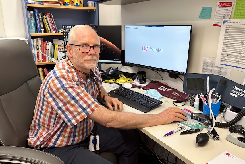 Dr McPhee sits at a desk with a computer.