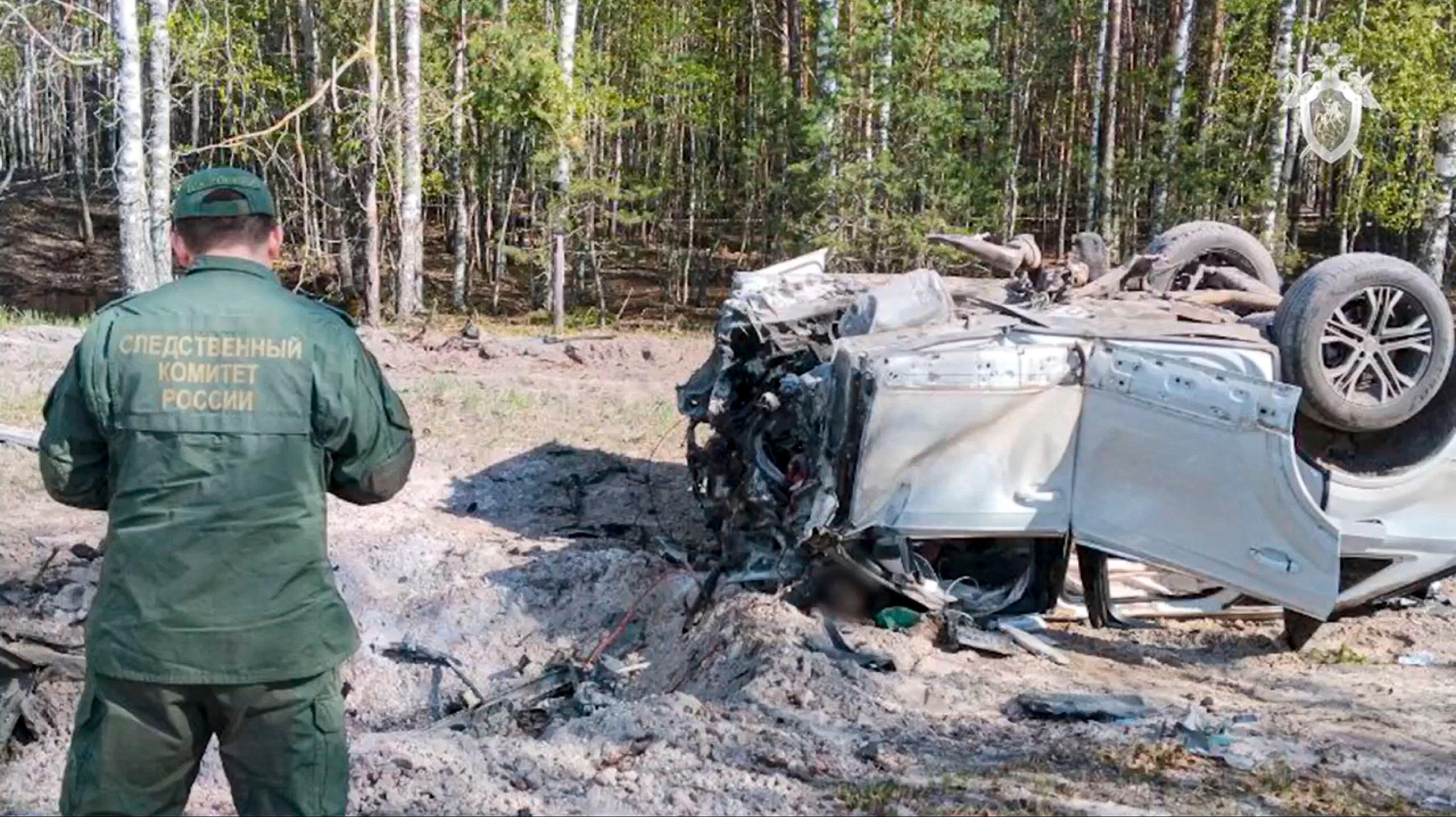 A Russian Investigative Committee employee works at the site of the exploded car which lays upside down.