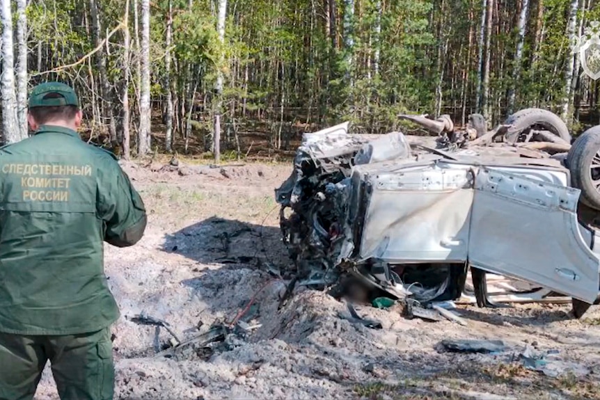 A Russian Investigative Committee employee works at the site of the exploded car which lays upside down.