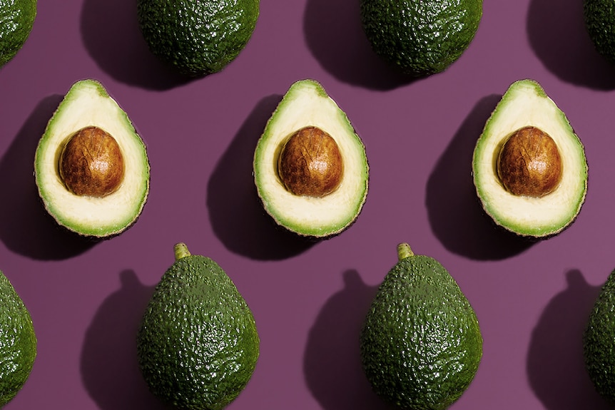 Halved avocados on a purple background, in a story about how to choose, store and eat Hass and Shepard avocados