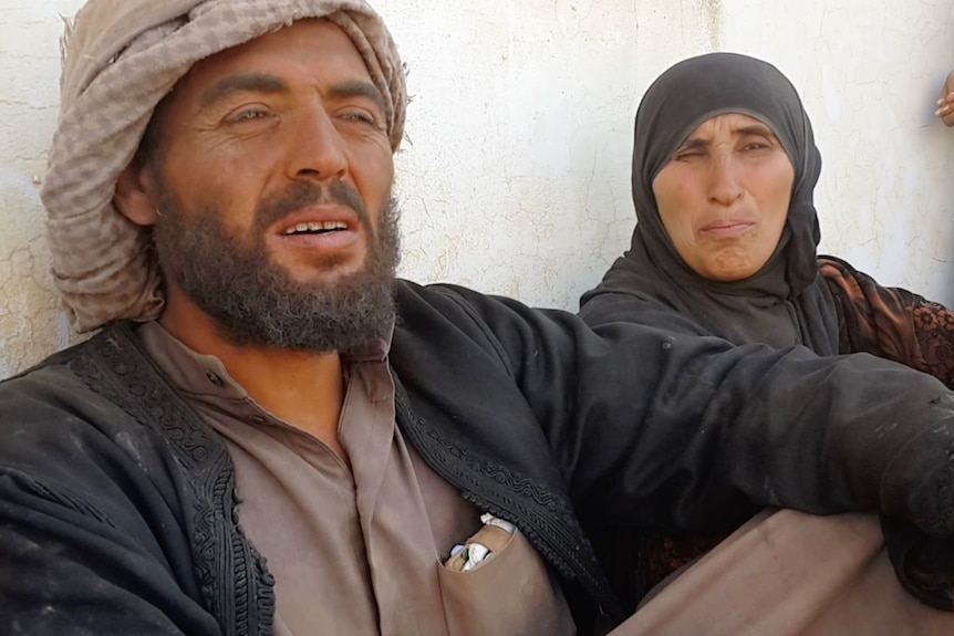 An exhausted man and woman sit leaning against a wall.