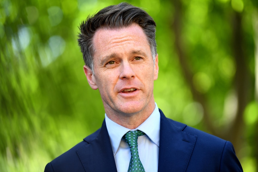 a man wearing a suit talking to the media outdoors