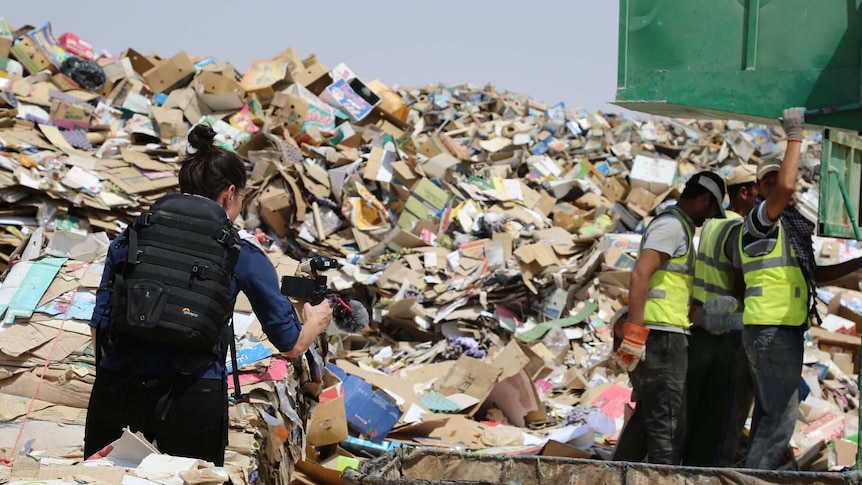 Journalist Ashlynne McGhee filming with a smartphone at a rubbish dump at a refugee camp in Jordan.