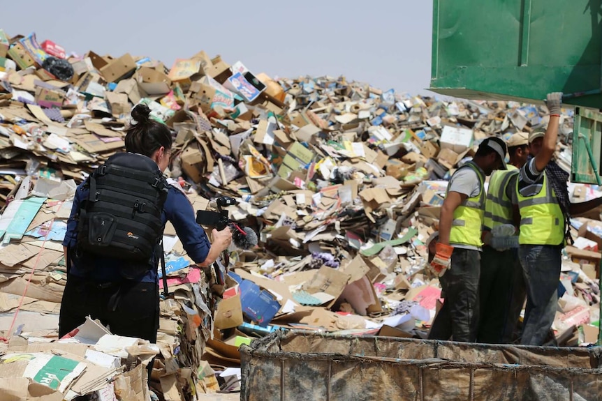 Journalist Ashlynne McGhee filming with a smartphone at a rubbish dump at a refugee camp in Jordan.