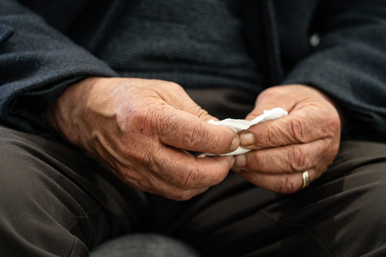 A man's hands holding a tissue