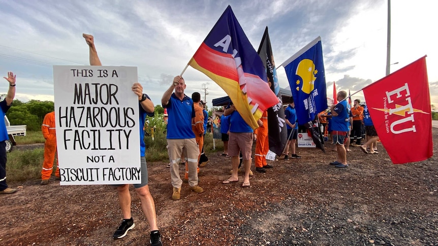 A crowd of men holding union flags and a poster that says 'This is a major hazardous facility, not a biscuit factory'.