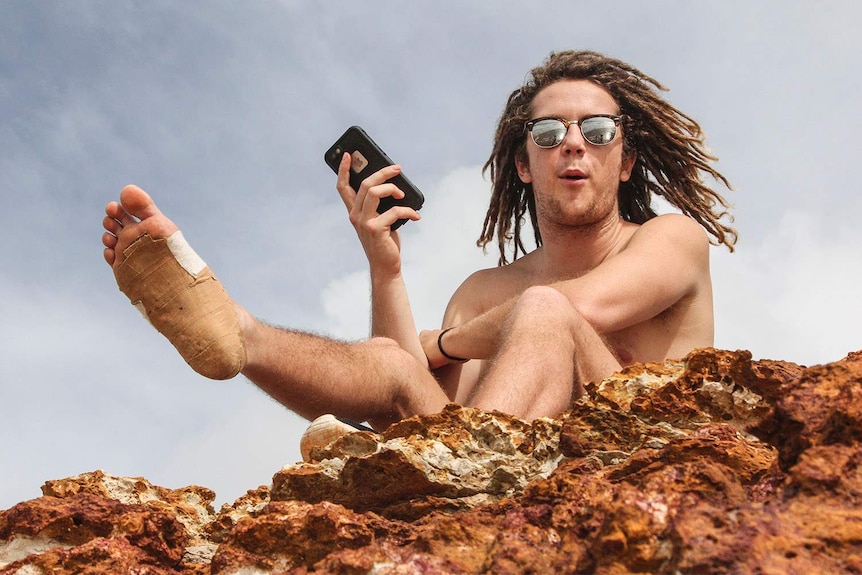 young man on rocks smiling