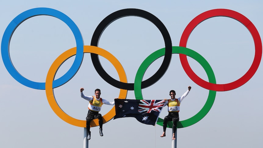 Mathew Belcher and Malcolm Page sit on the Olympic rings after winning 470 gold