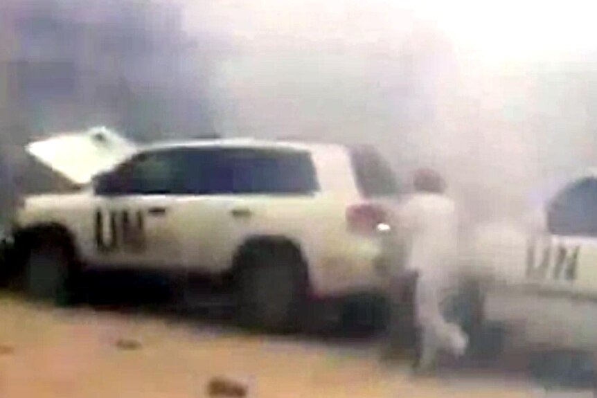 A man runs to a UN vehicle seconds after a roadside bomb exploded in front of a UN convoy.