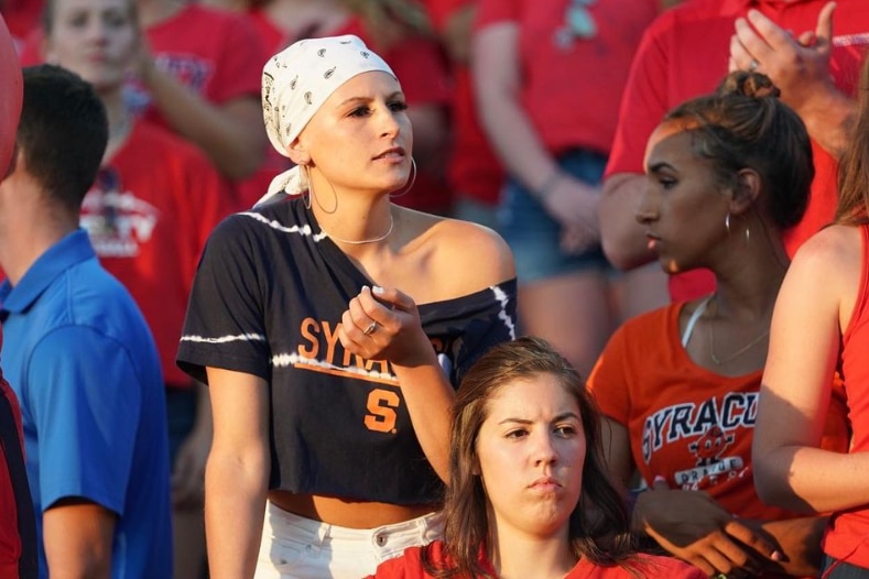 Tiana Mangakahia is watching a sporting event in the crowd, she wears a white bandanna to cover her head.