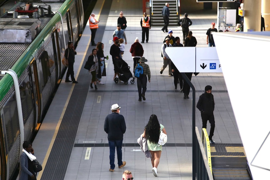 People walk off a train and onto a platform at Perth Train Station.